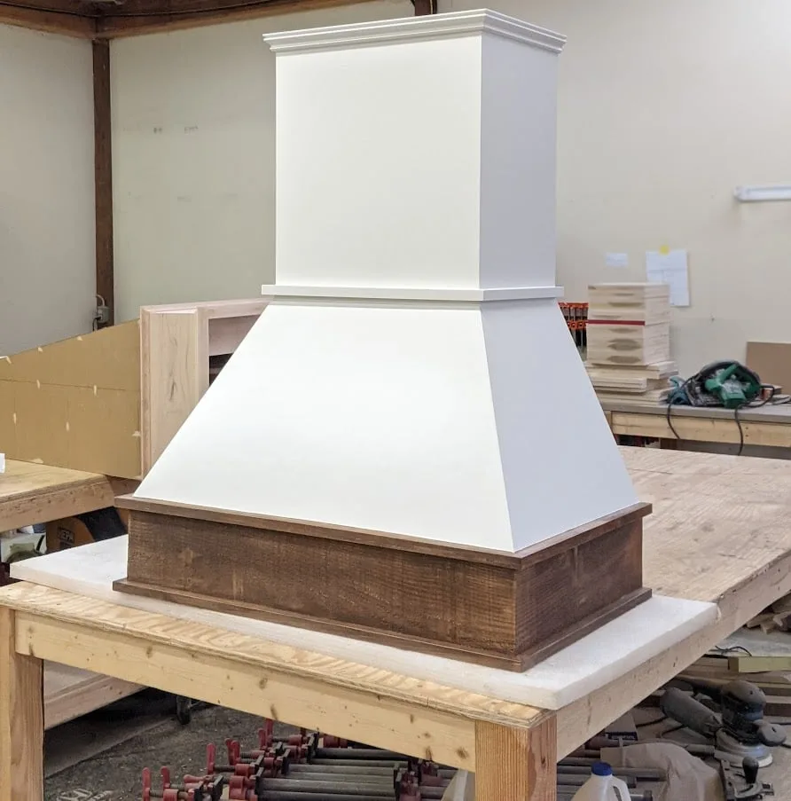 Chimney range hood with a reclaimed wood base on the workshop table