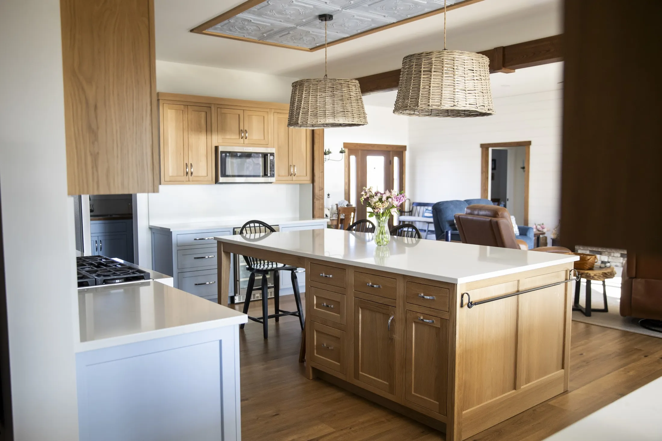 Oak kitchen island, woven pendants and blue-gray perimeter cabinets